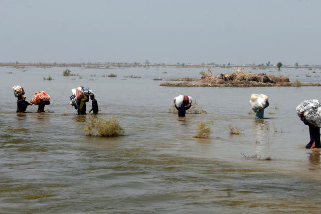 Victims of heavy flooding from monsoon rains crowd carry relief aid through flood water in Sindh Province (Fareed Khan/AP) File)