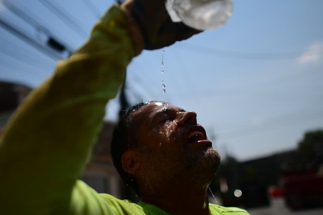 <p>A construction pours water on his face to stay cool in Philadelphia during a heatwave this August</p>