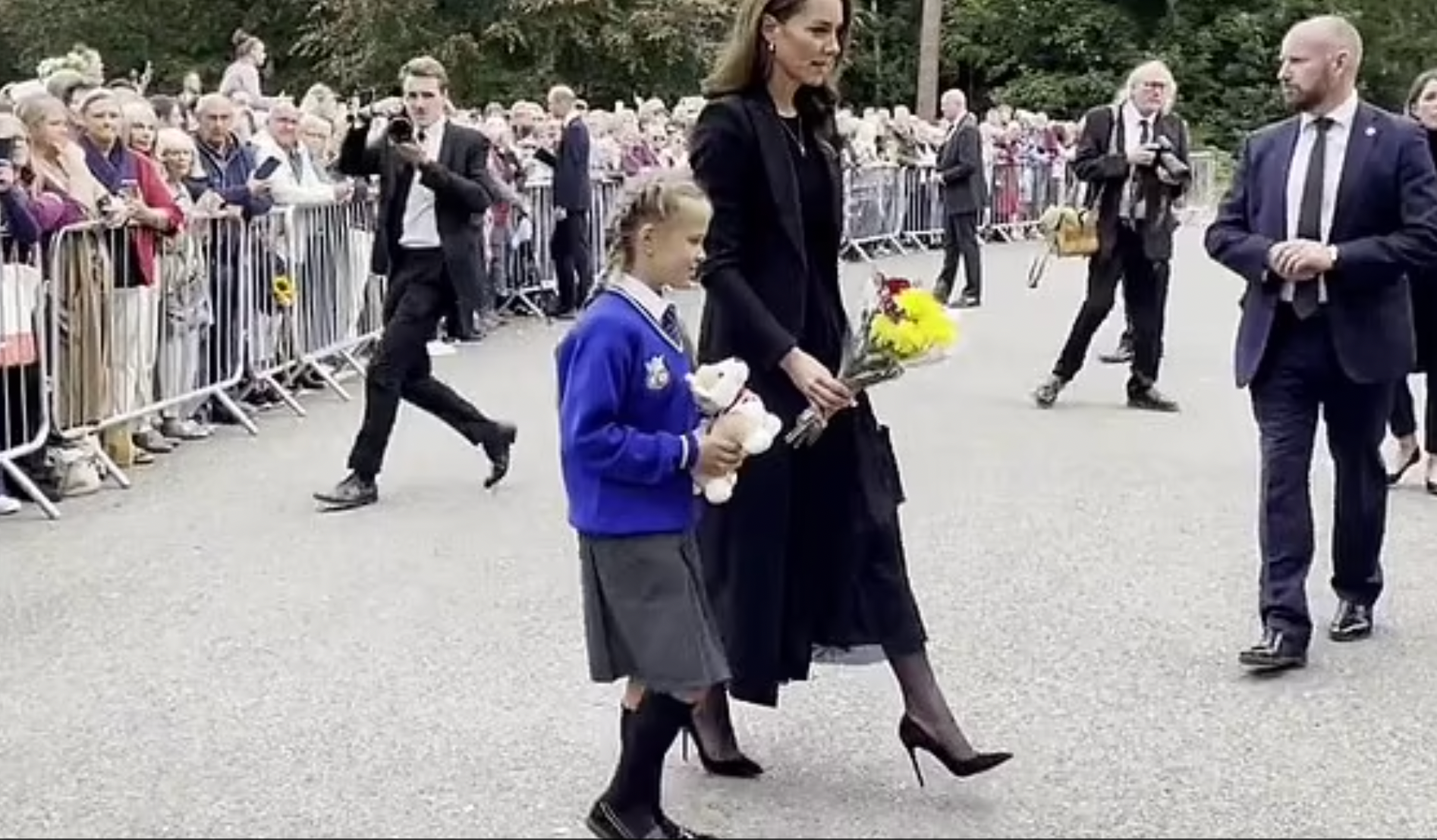 A screenshot of Princess Kate and Elizabeth Sulkovska laying a toy corgi and flowers among the tributes left to the Queen