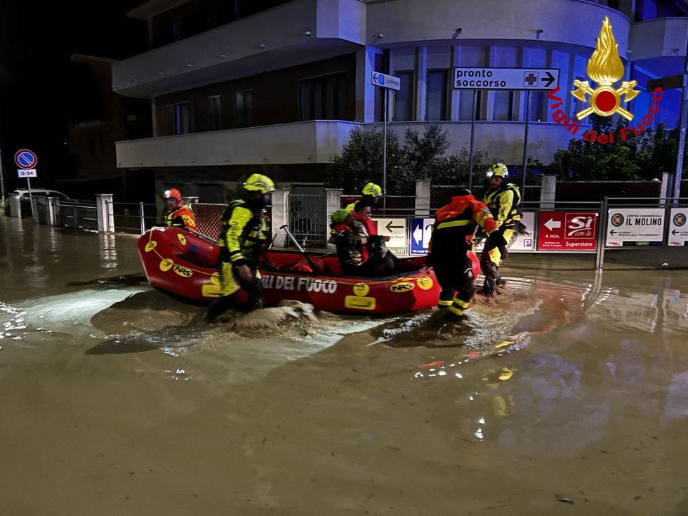 Rescue workers help people in a dinghy on a flooded street after heavy rains hit the seaside town of Senigallia