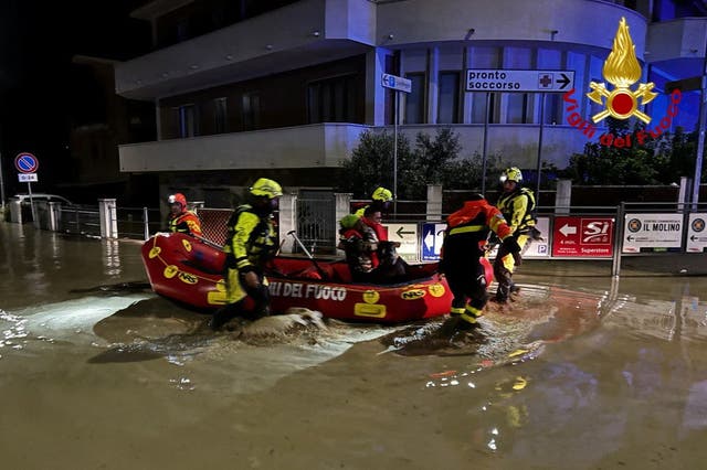 <p>Rescue workers help people in a dinghy on a flooded street after heavy rains hit the seaside town of Senigallia</p>