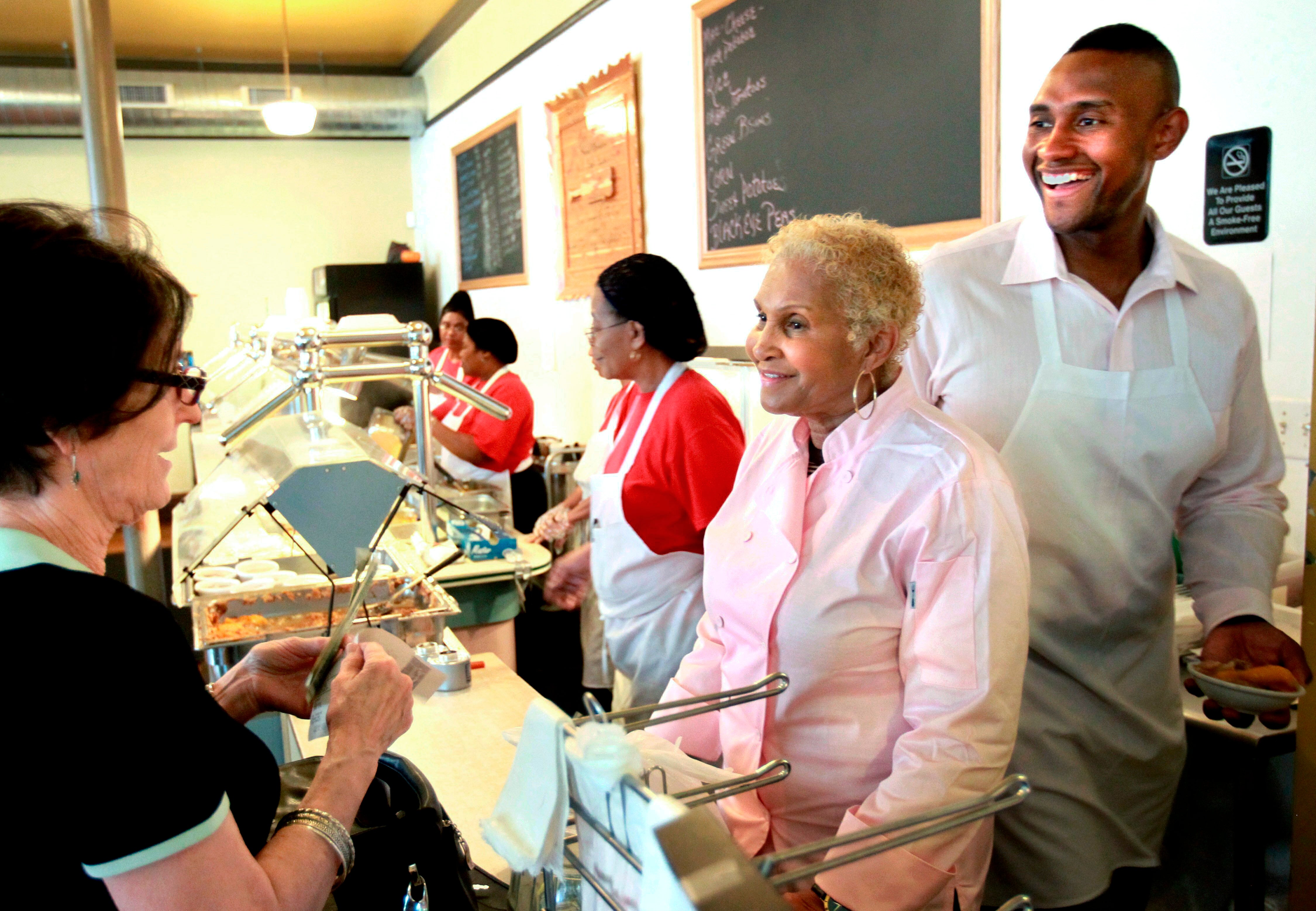 A customer picks up food from Sweetie Pie’s owner Robbie Montgomery, second right, and Montgomery’s son, James “Tim” Norman