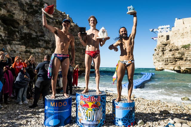 (L-R) Aidan Heslop of the UK, Gary Hunt of France and Catalin Preda of Romania celebrate on the podium during the final competition day of the seventh stop of the Red Bull Cliff Diving World Series at Polignano a Mare, Italy on September 18, 2022. (Romina Amato/Red Bull Content Pool/PA)