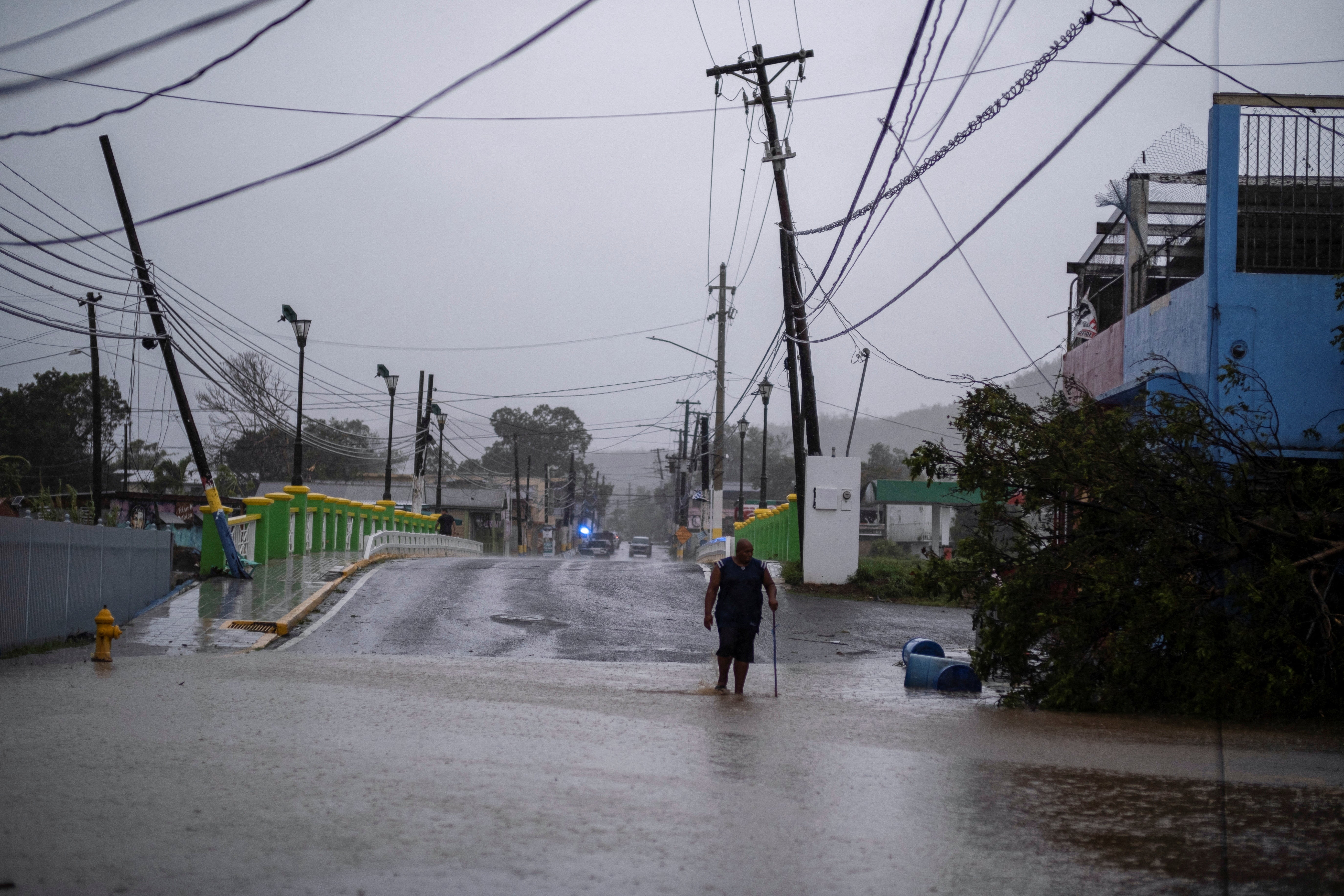 A man wades through a flooded street after Hurricane Fiona affected the area in Yauco, Puerto Rico