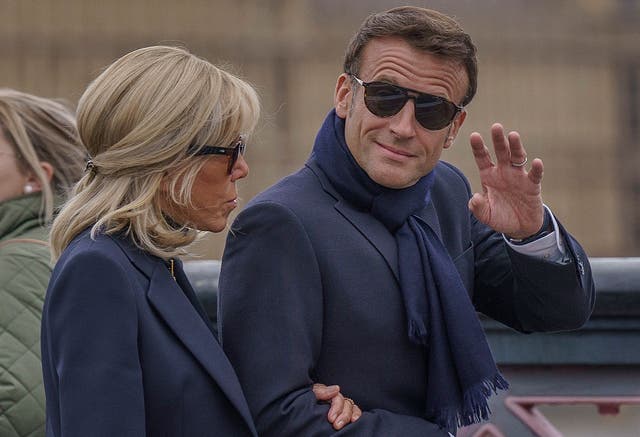 <p>French President Emmanuel Macron waves as he and his wife Brigitte Macron walk along a bridge with the Palace of Westminster in the background in London on Sunday </p>