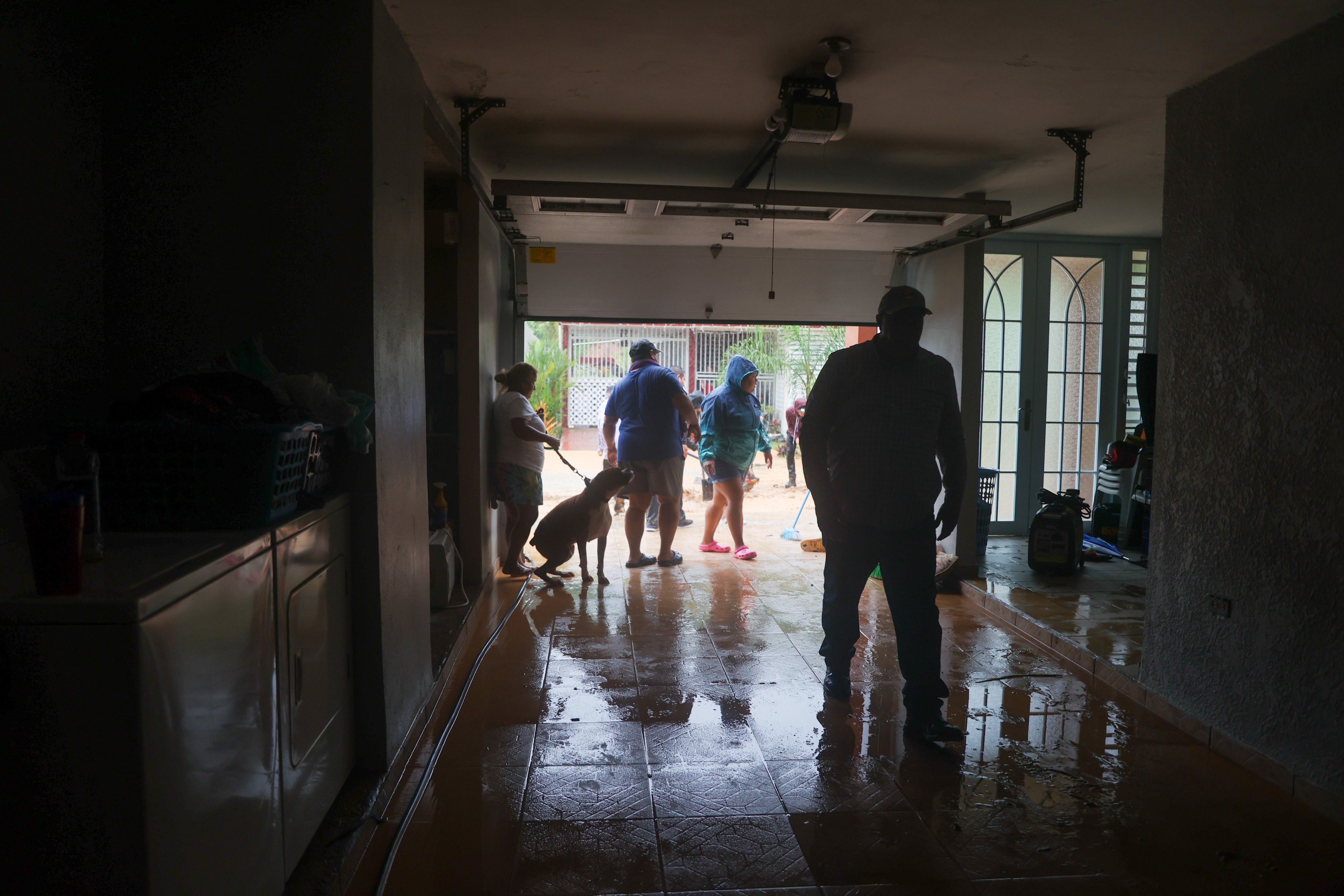 People clean a house flooded by the rains of Hurricane Fiona