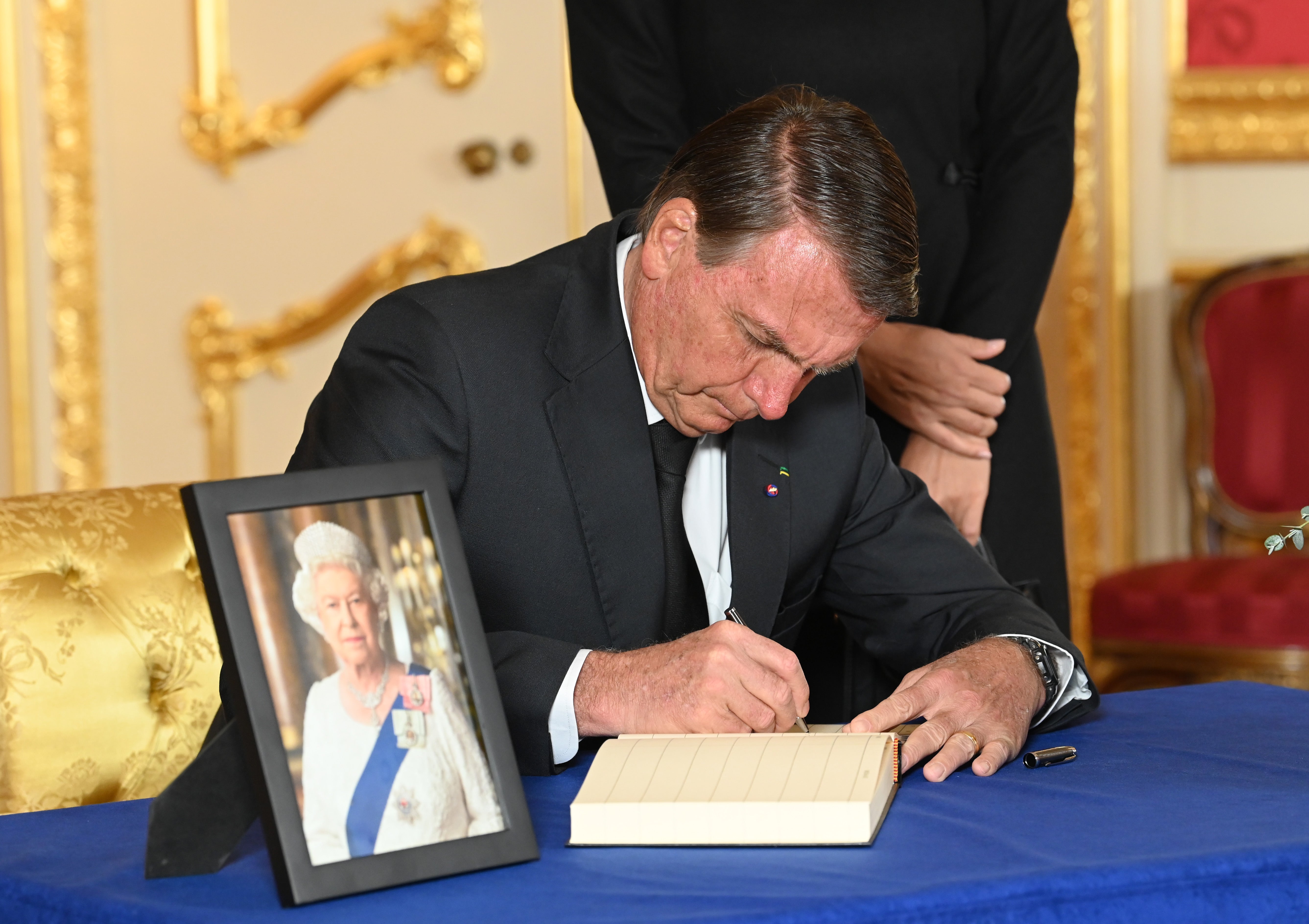Brazilian President Jair Bolsonaro signs a book of condolence at Lancaster House on September 18, 2022 in London