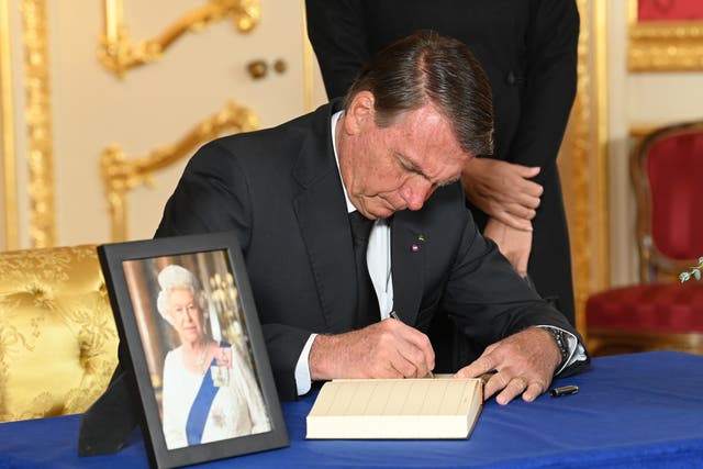 <p>Brazilian president Jair Bolsonaro signs a book of condolence in London on 18 September, 2022.  </p>