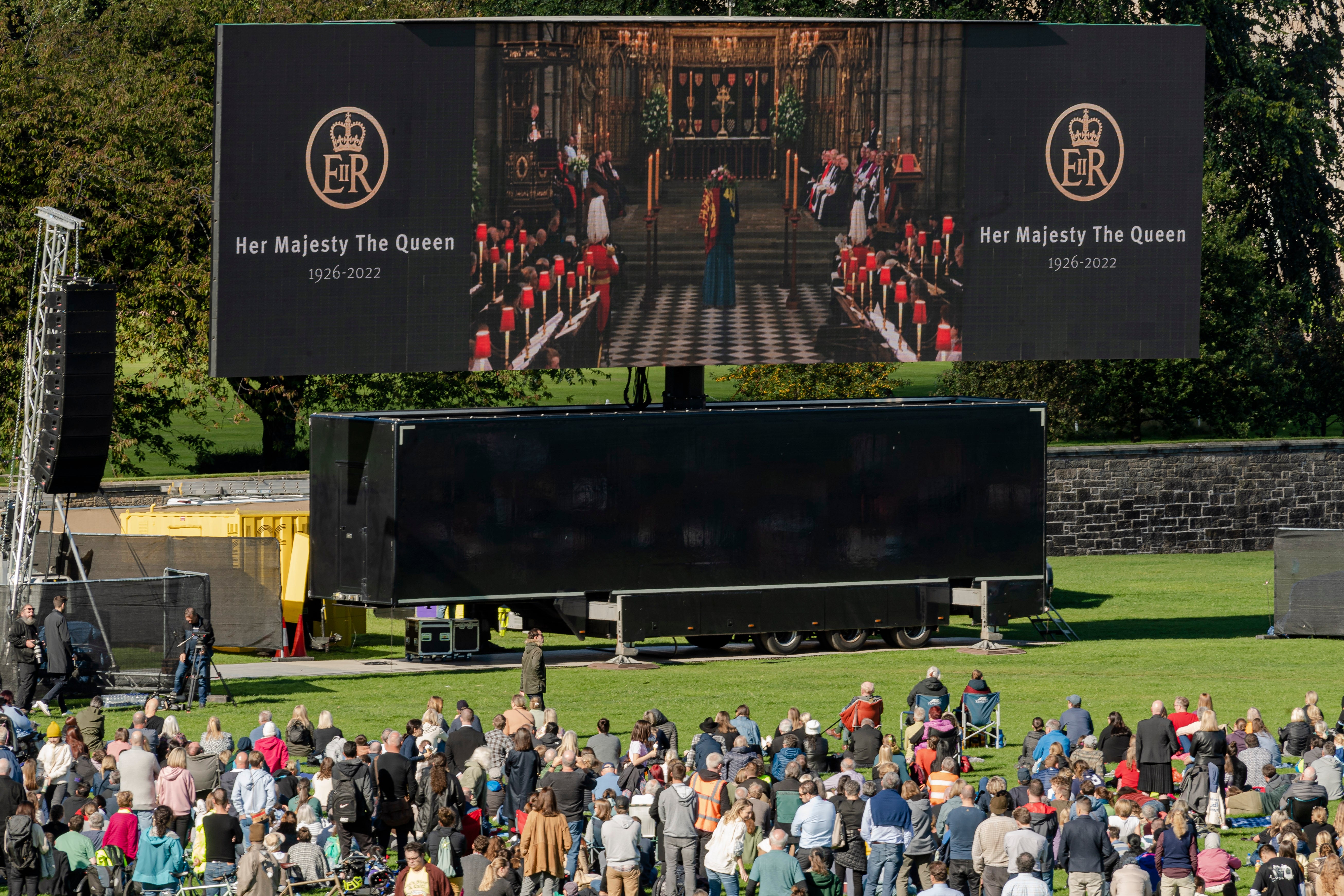 Members of the public watch Queen Elizabeth II’s state funeral on a TV screen in Holyrood Park, Edinburgh