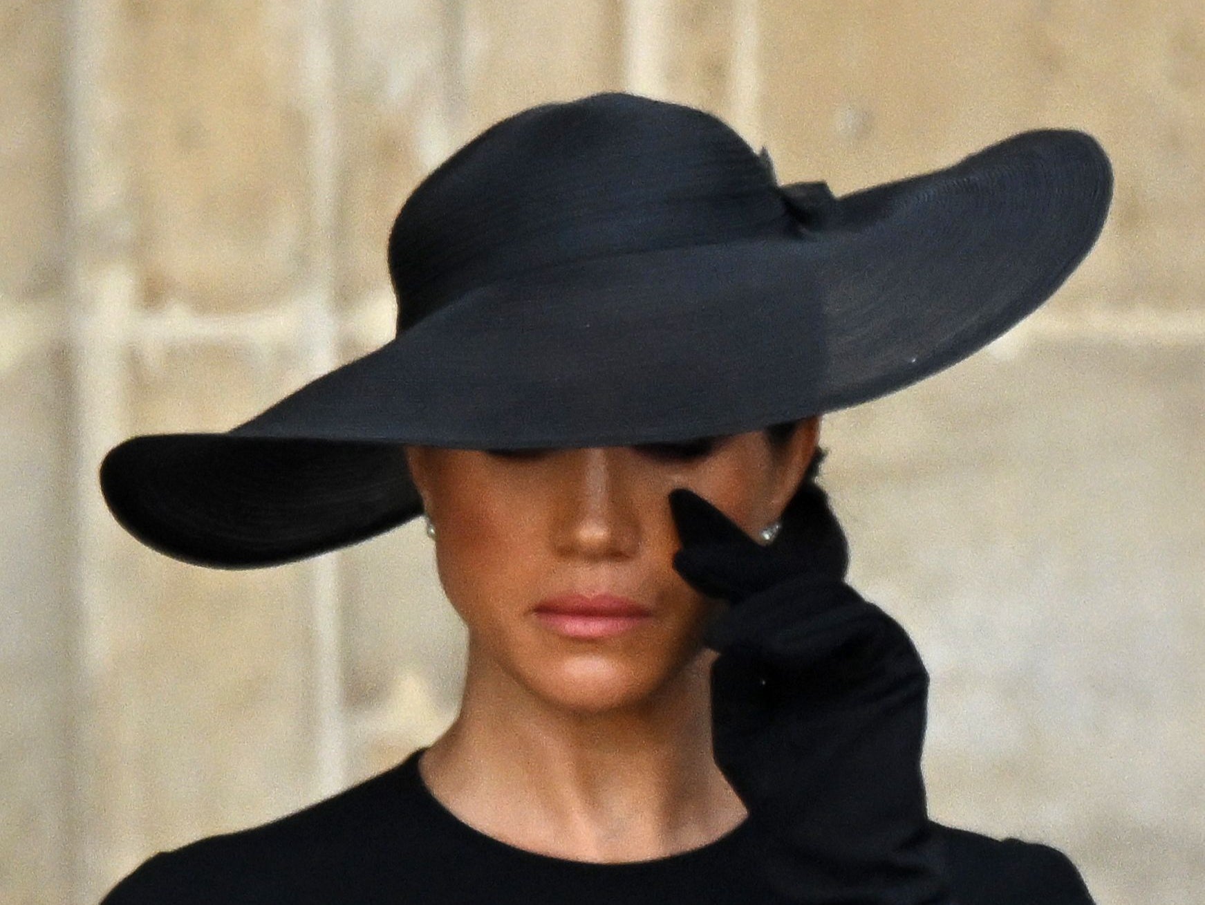 Meghan Markle appears to wipe away tears during the Queen's funeral. She has not visited the UK since it took place in September 2022.