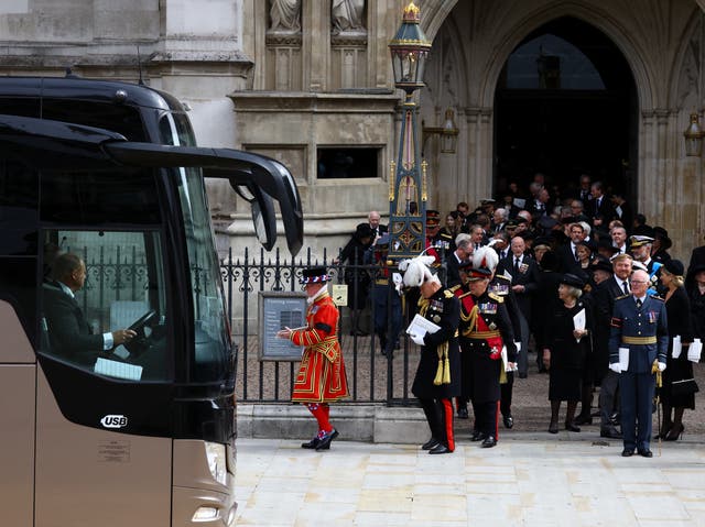 Los invitados esperan para abordar un autobús fuera de la Abadía de Westminster después del funeral de estado de la reina Isabel II