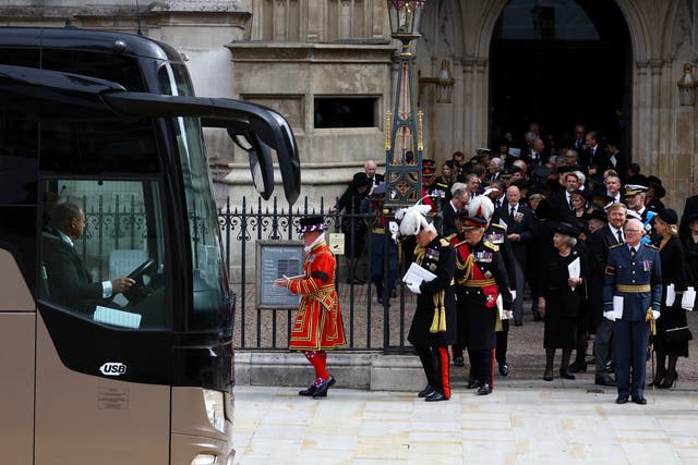 Los invitados esperan para abordar un autobús fuera de la Abadía de Westminster después del funeral de estado de la reina Isabel II