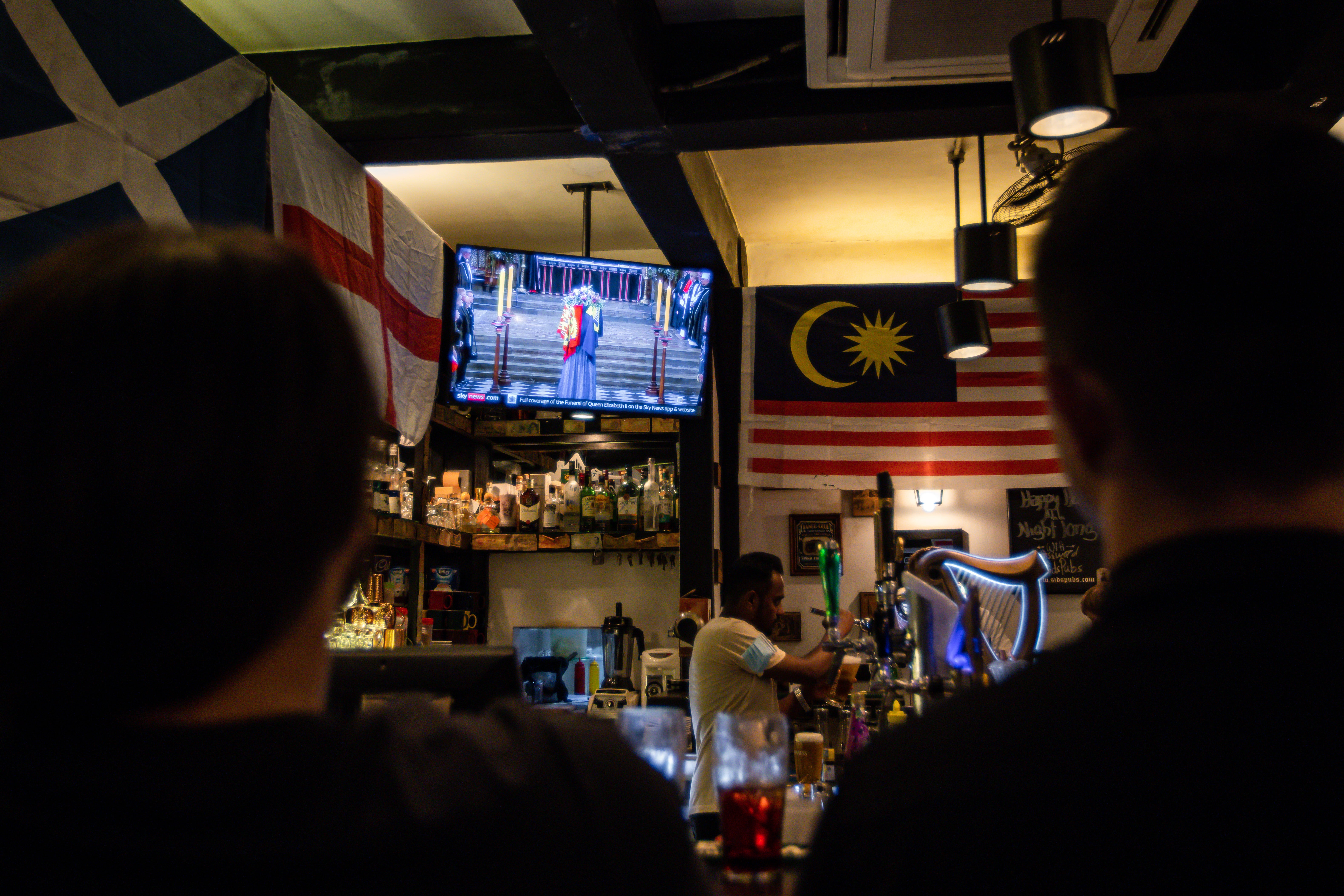 Foottage of the funeral being broadcast at a British pub in Kuala Lumpur, Malaysia
