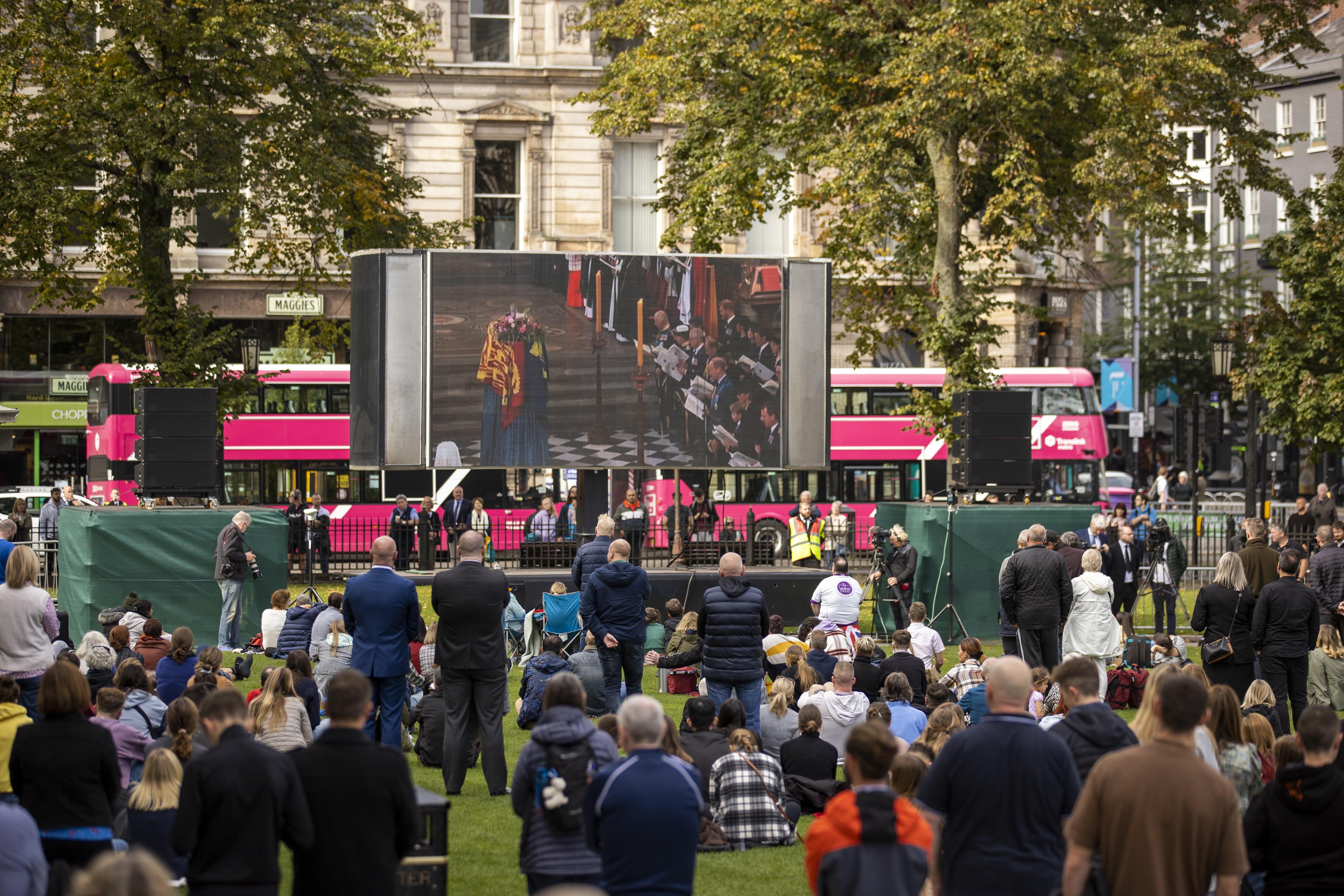 People in the grounds of Belfast City Hall watch Queen Elizabeth II funeral on a large screen. Picture date: Monday September 19, 2022.