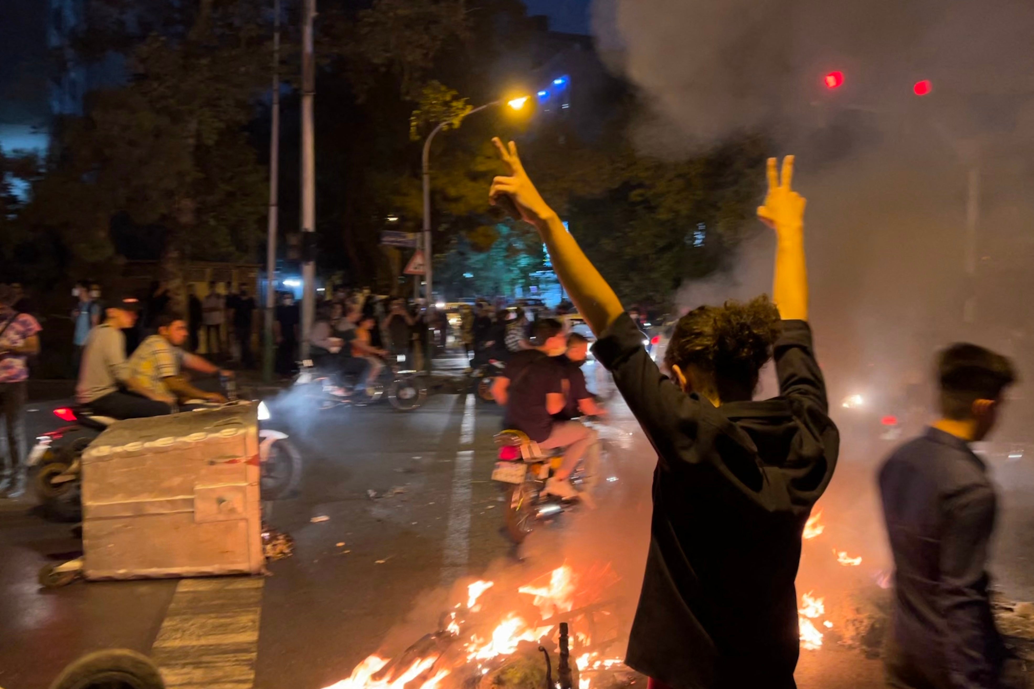A demonstrator raises his arms and makes the victory sign during a protest for Mahsa Amini