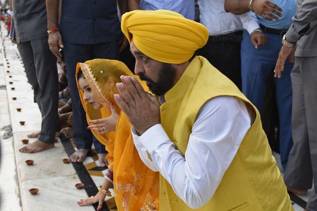 <p>India’s Punjab state chief minister Bhagwant Mann (C) along with his wife Gurpreet Kaur pay respect on the occasion of the 418th anniversary of the installation of the Guru Granth Sahib (Sikh holy book) at the Golden temple in Amritsar on August 28, 2022.</p>