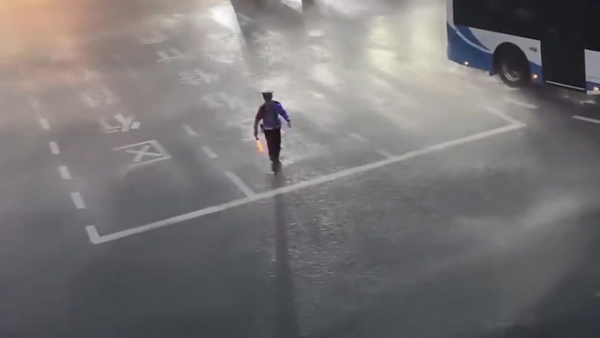 Dedicated traffic officer braves torrential storm in China to direct cars