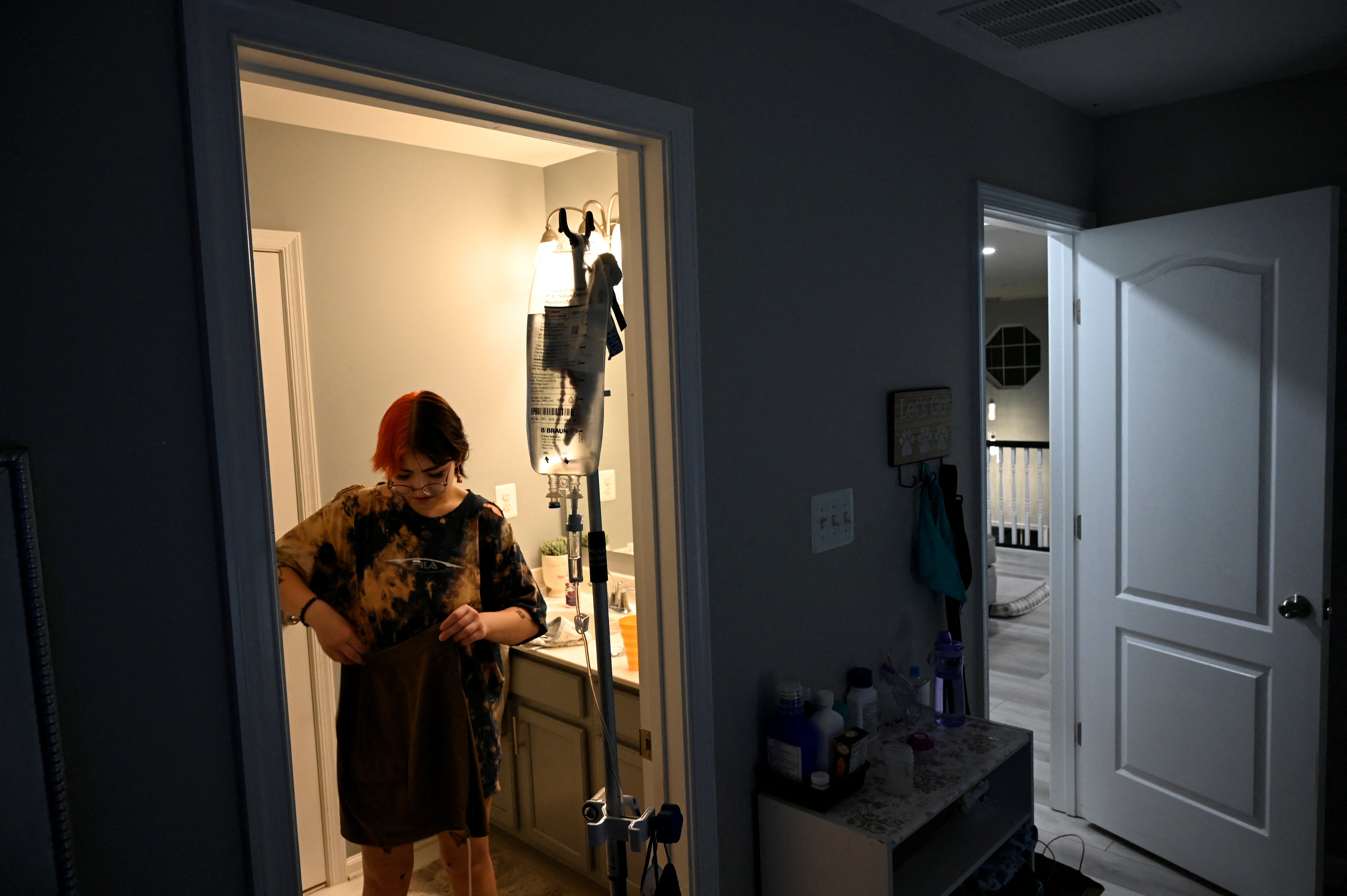 Logan tidies up their room while they carry their IV bag