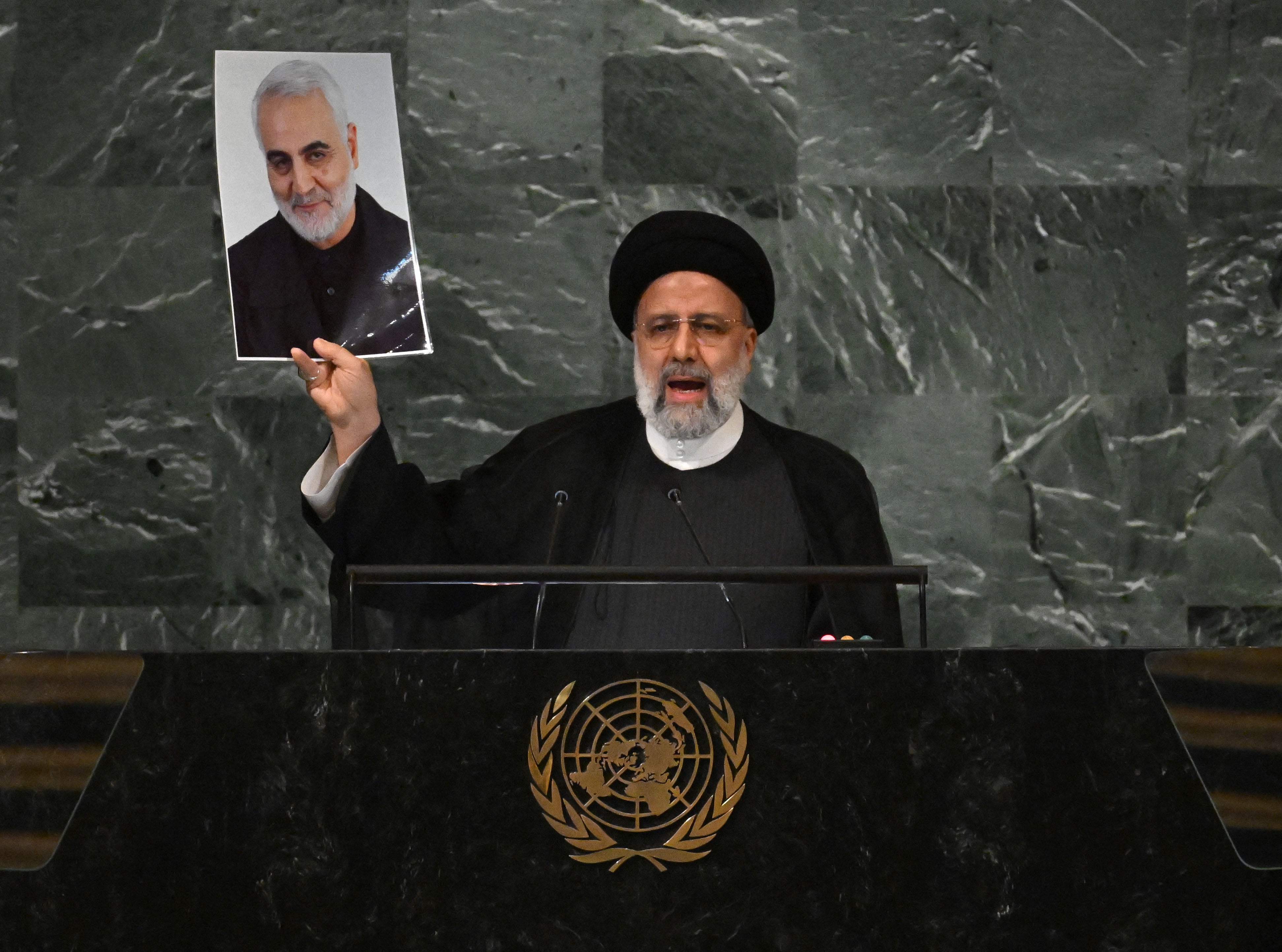 Iranian President Ebrahim Raisi addresses the 77th session of the United Nations General Assembly while holding a photo of Iranian General Qasem Soleimani killed by a US drone strike in Baghdad in January 2020
