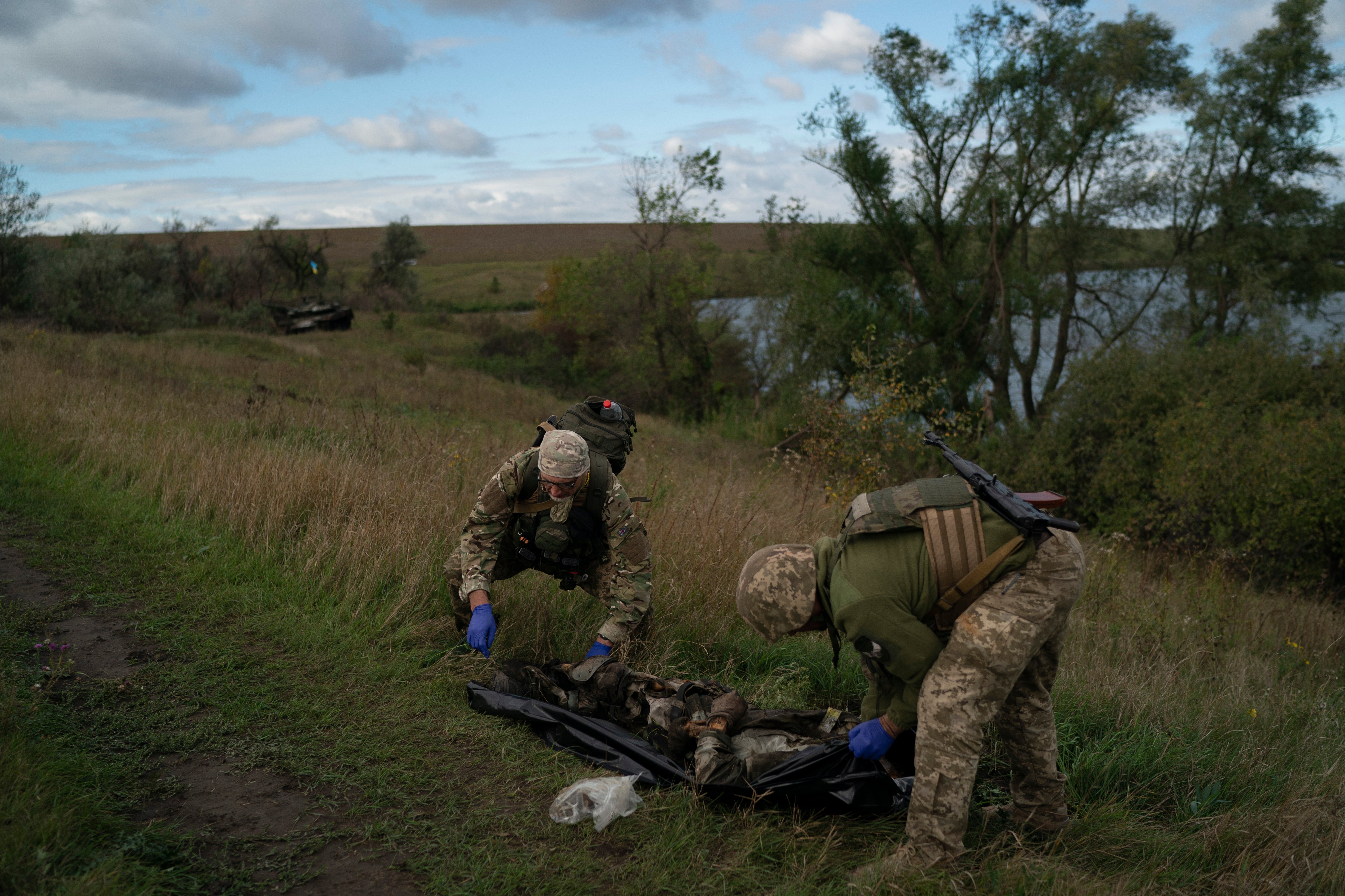 Ukrainian National Guard servicemen place the body of a Ukrainian soldier in a bag at an area near the border with Russia, in Kharkiv region, Ukraine