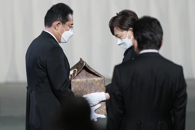 <p>Akie Abe, wife of former prime minister Sinzo Abe, hands a cinerary urn containing his ashes to his successor Fumio Kishida</p>