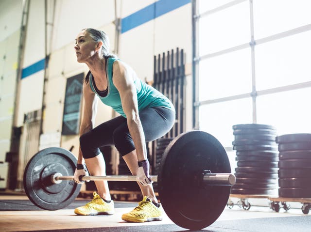 <p>A  woman in her 50’s prepares to do an . snatch and clean in a cross training setting</p>
