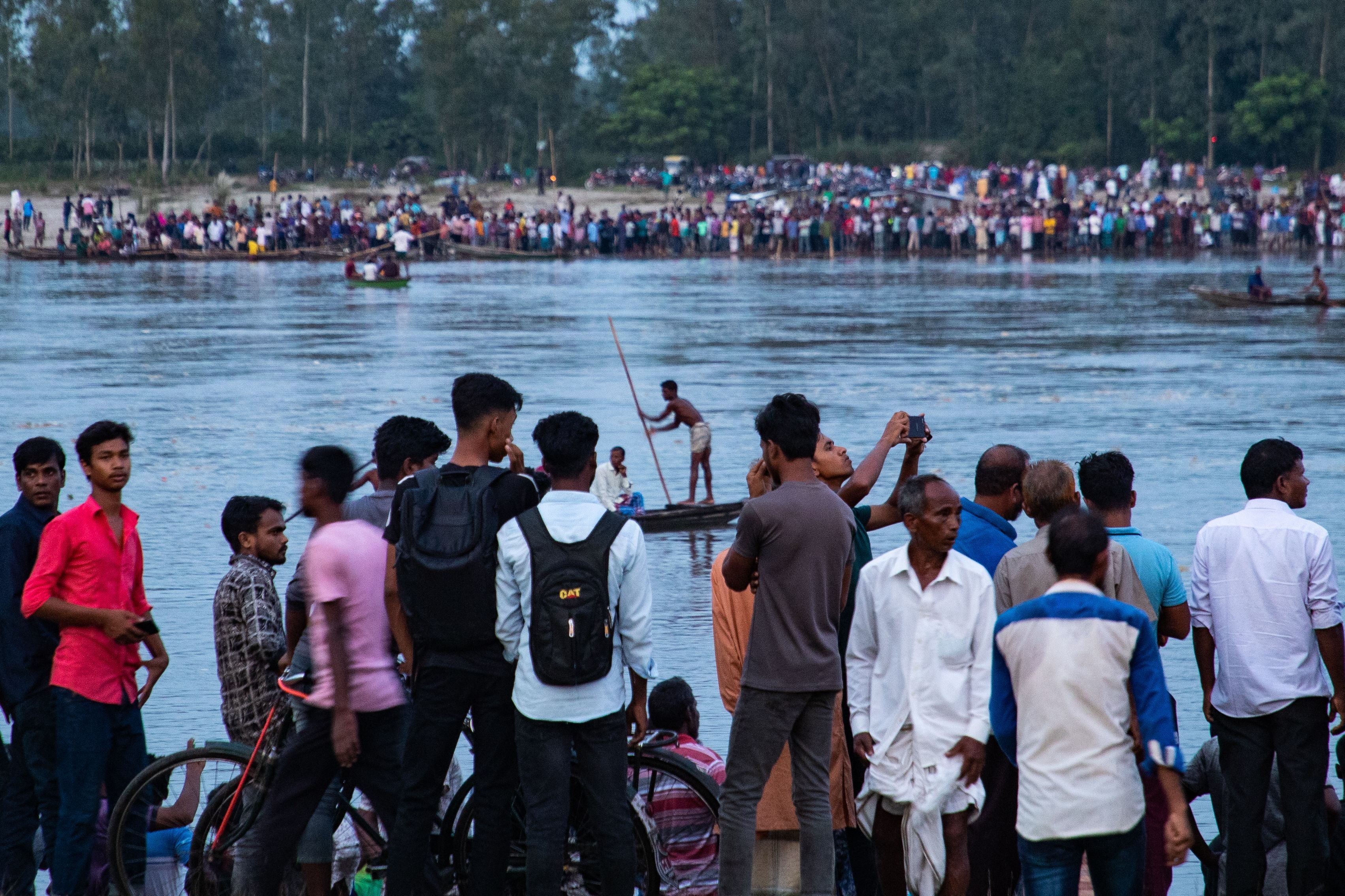 In this picture taken on 25 September 2022, people gather along the banks of the Karatoa river after a boat capsized near the town of Boda