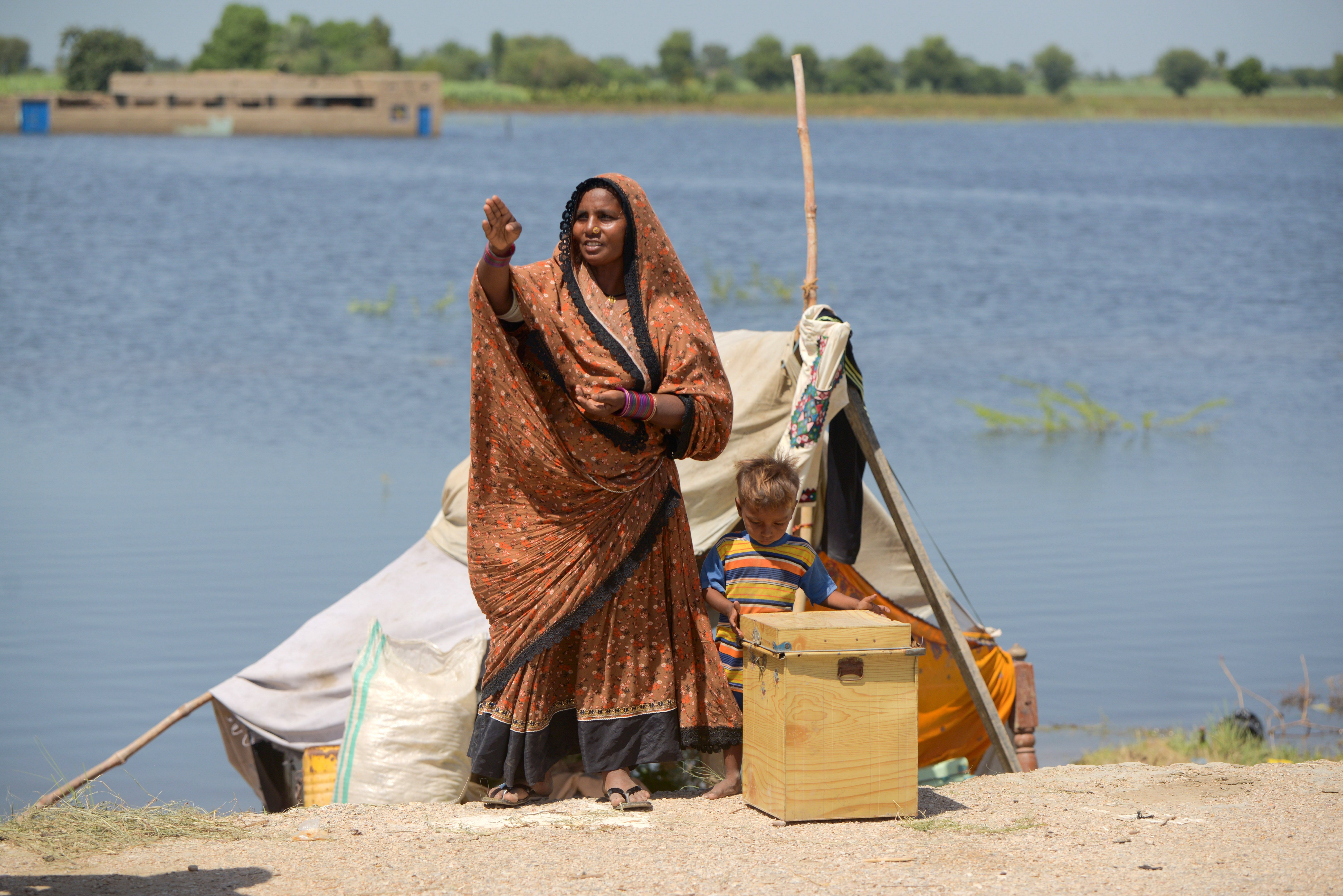Soni, 37, stands with her family in front of her temporary shelter in Sindh