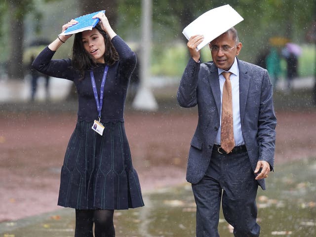 <p>Workers try to shelter from the rain in London on Tuesday </p>