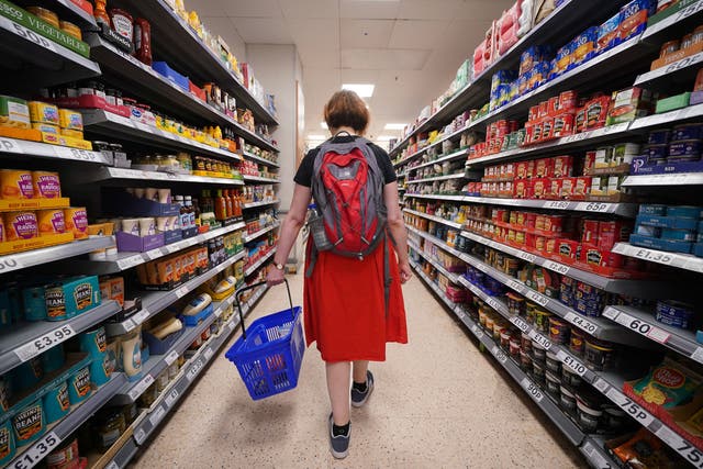 <p>A shopper walks through a Tesco’s aisle in London </p>