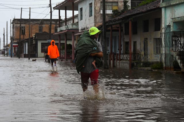 <p>People walk through a flooded street in Batabano, Cuba, on September 27, 2022, during the passage of hurricane Ian</p>