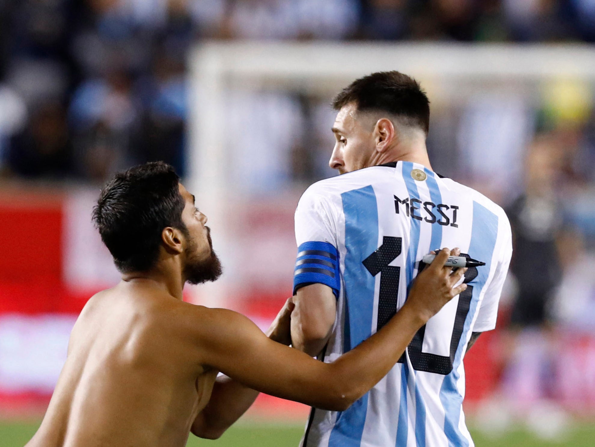 A fan approaches Lionel Messi before asking the Argentina captain to sign his back