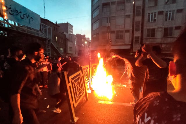 <p>Protesters make fire and block the street during a protest over the death of a woman who was detained by the morality police, in downtown Tehran, Iran</p>