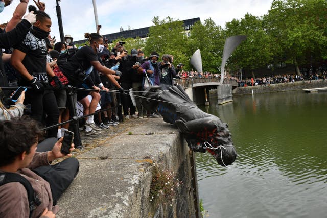 <p>Protesters throwing the statue of Edward Colston into Bristol harbour</p>