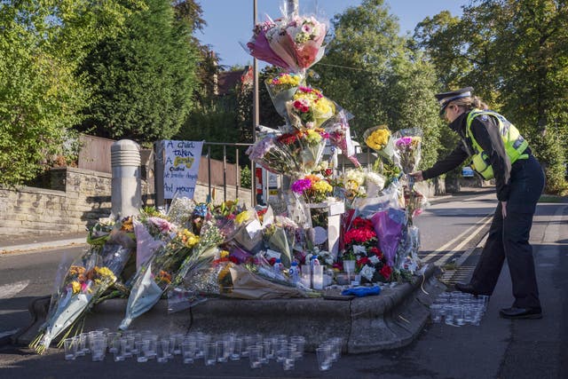 A police community support officer lays a floral tribute at the scene in Woodhouse Hill (Danny Lawson/PA)