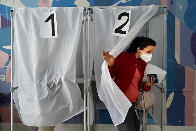 <p>A woman holds her ballot as she leaves a voting booth at a polling station during a referendum in Melitopol</p>