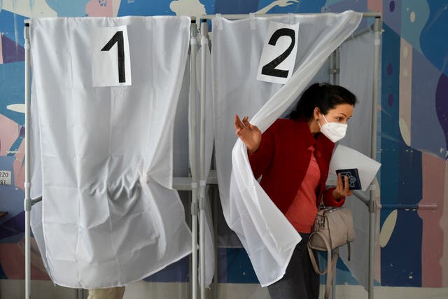 Una mujer sostiene su boleta al salir de una cabina de votación en un colegio electoral durante un referéndum en Melitopol.