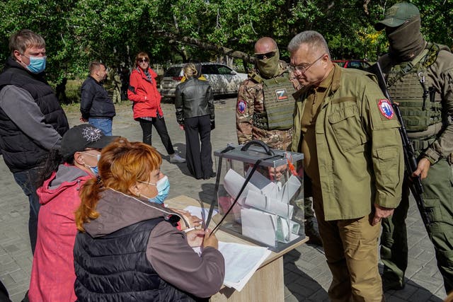 <p>Mayor of occupied Mariupol, Konstantin Ivashchenko, stands near armed servicemen at a polling station</p>