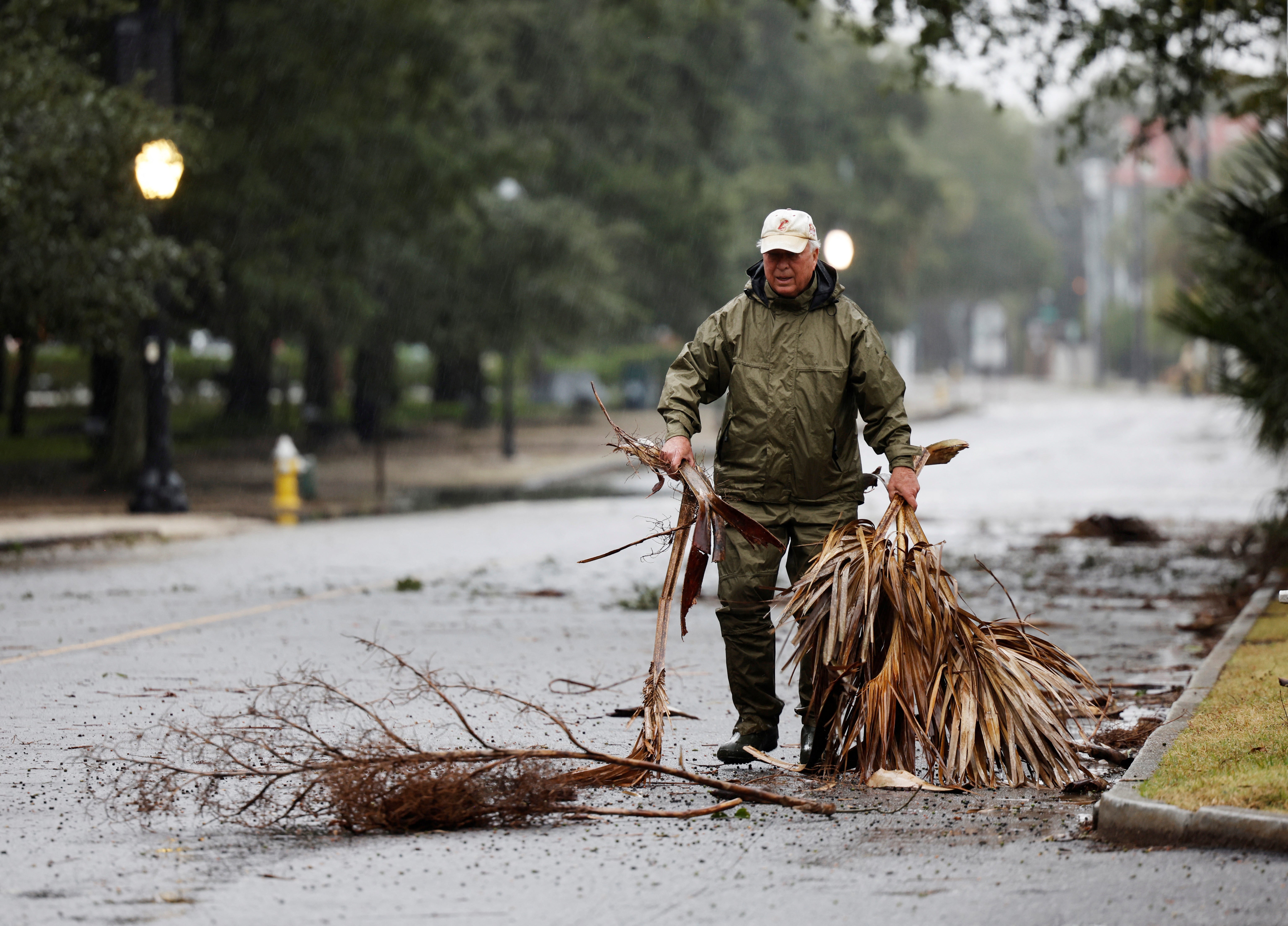 A man clears branches from a road in Charleston to keep the gutters clear when Hurricane Ian arrives on Friday