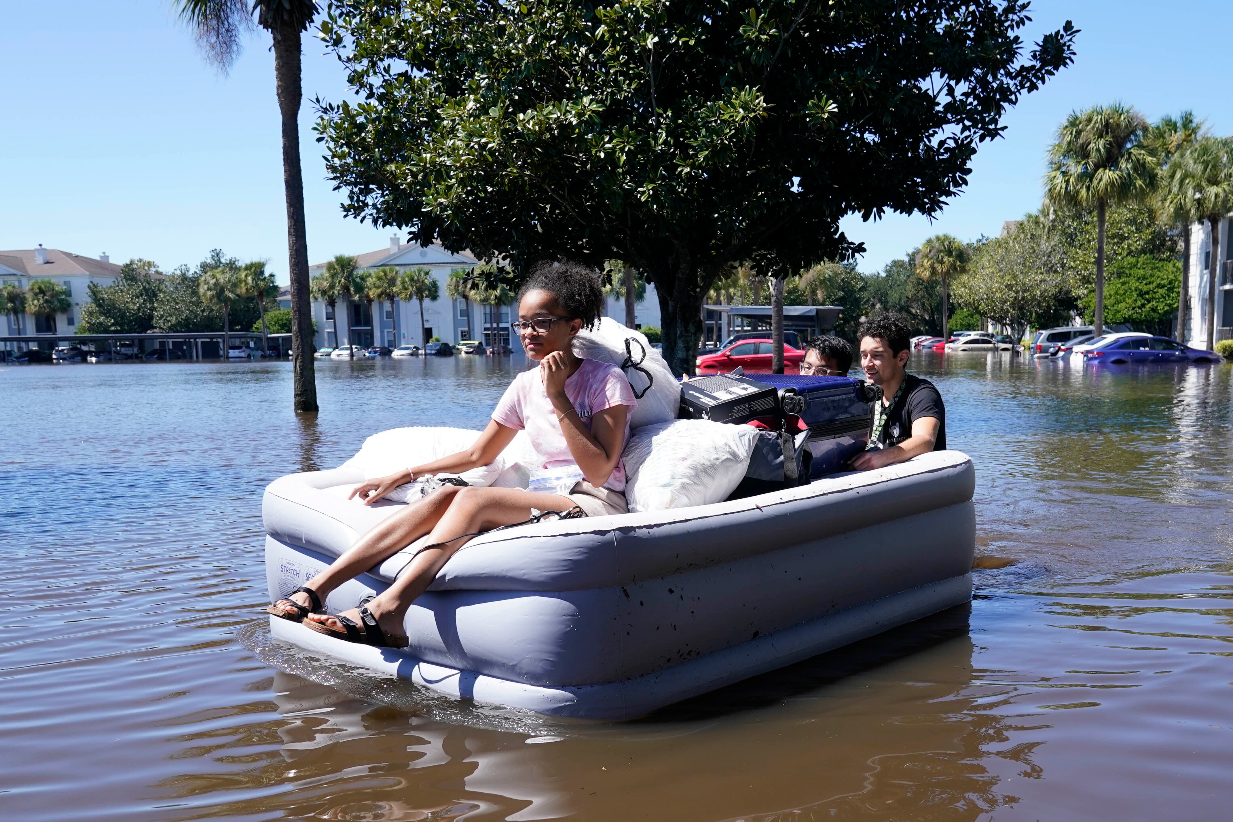University of Central Florida students use an air mattress to leave a flood apartment complex in Orlando on Friday