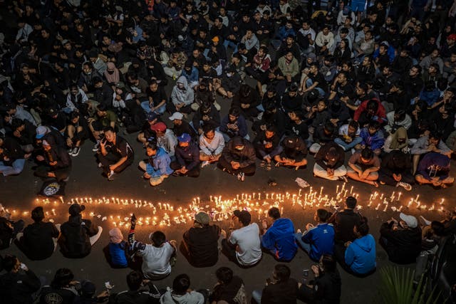 Los seguidores del club de fútbol Arema encienden velas mientras rezan por las víctimas el 2 de octubre de 2022 en Malang, Indonesia.