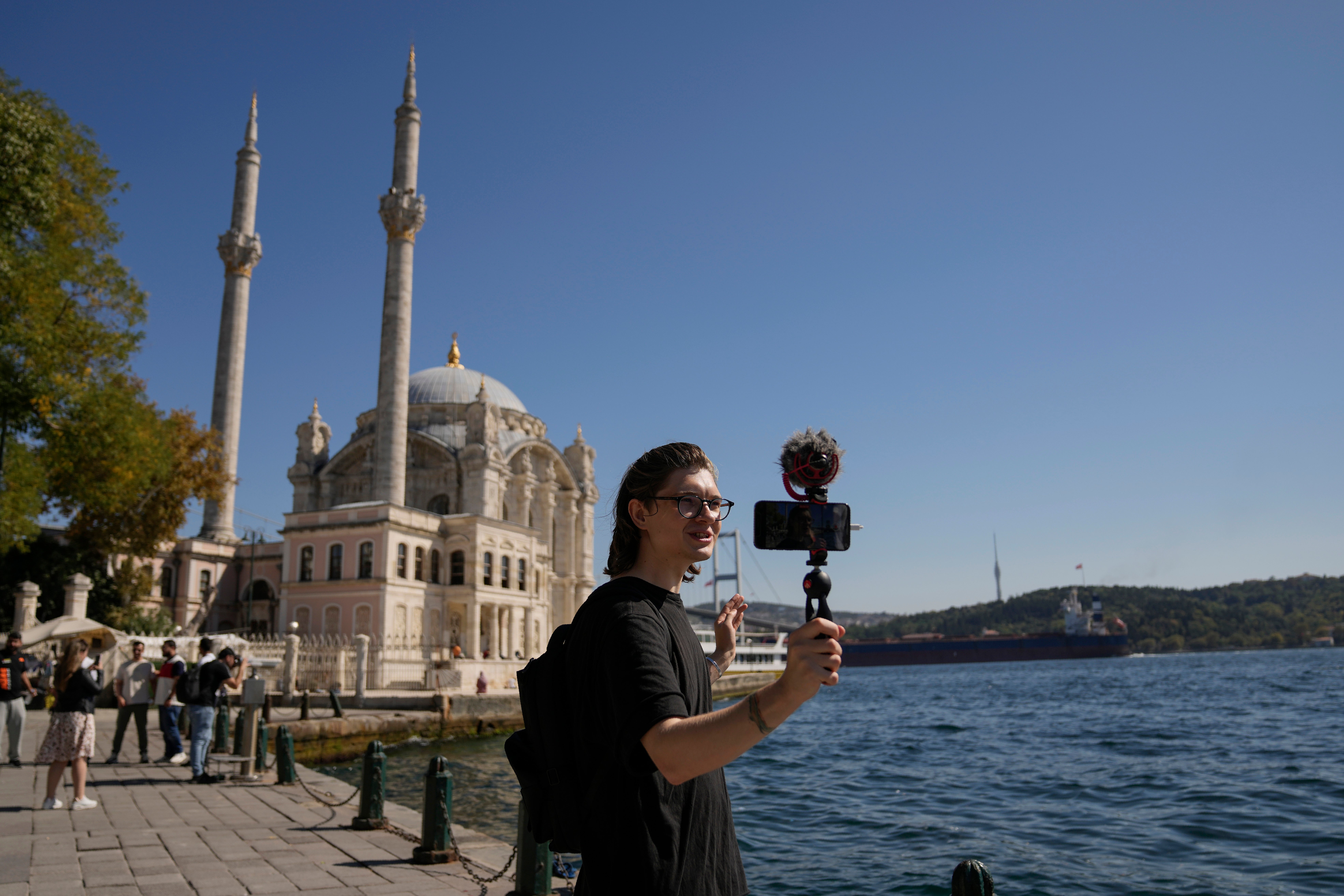 Vlogger Niki shoots for his YouTube channel while wandering next to the historic Ortakoy Mosque in Istanbul