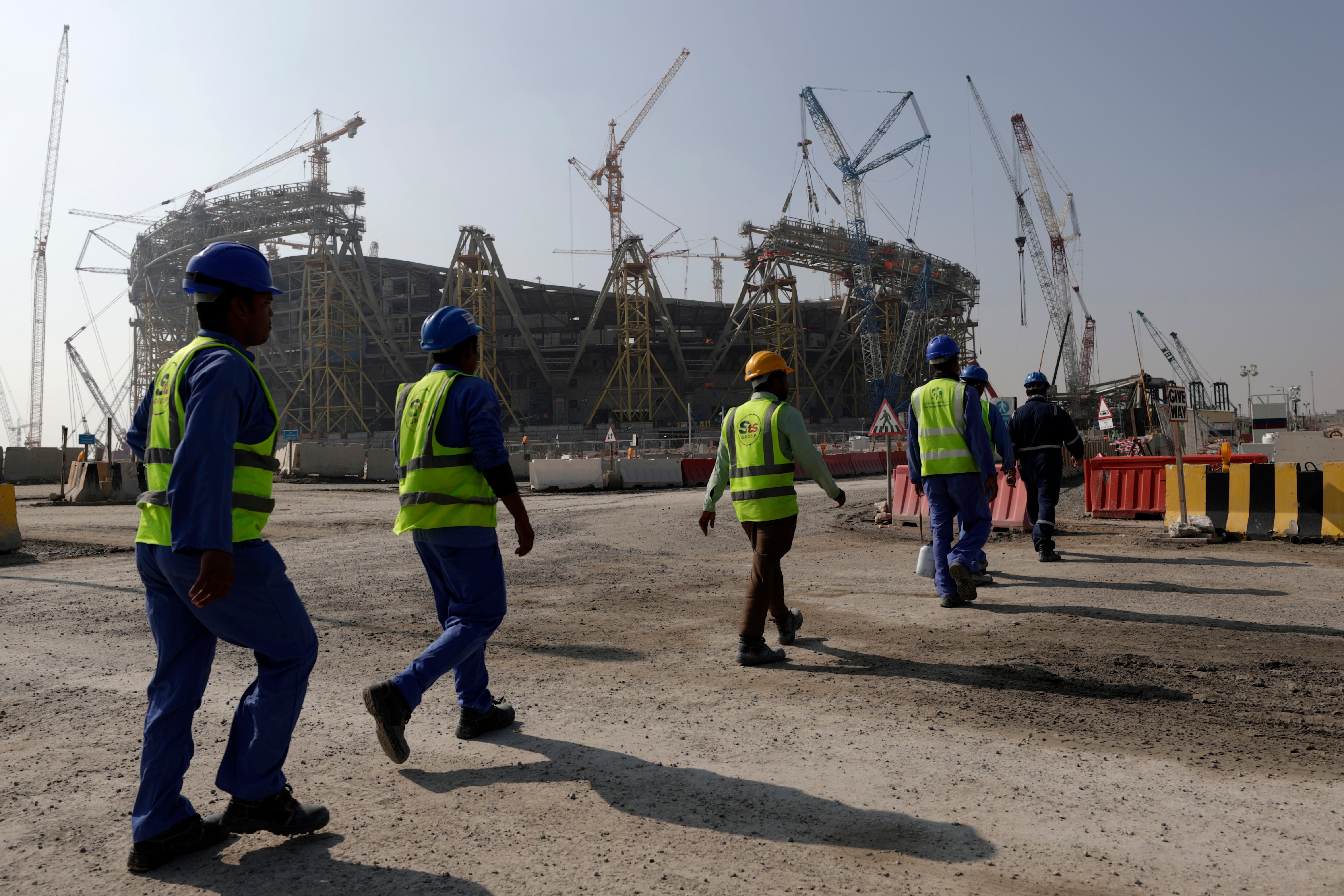 Workers walk to the Lusail Stadium