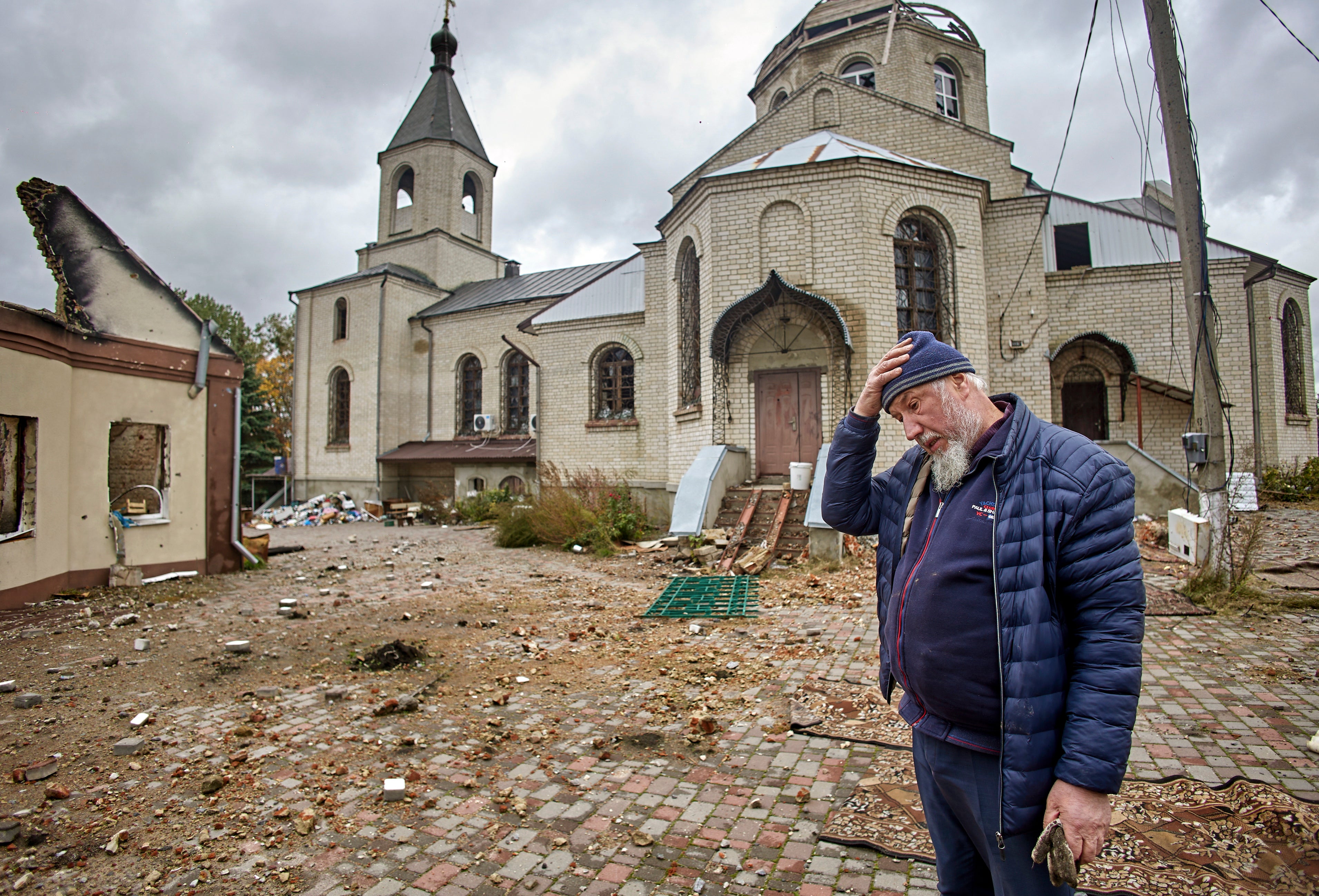 A priest reacts near a damaged church in the Ruska Lozova village in the Kharkiv area