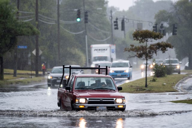 <p>A car drives through a flooded street as the remnants of Hurricane Ian batter Norfolk, Virginia on Monday</p>