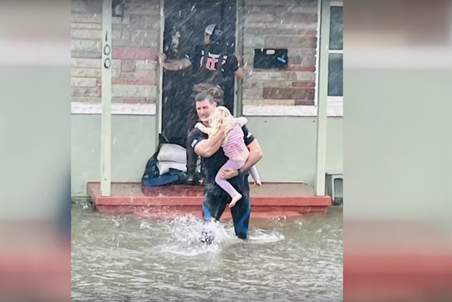 <p>A firefighter rescues a girl from floods in St Augustine, Florida last week </p>