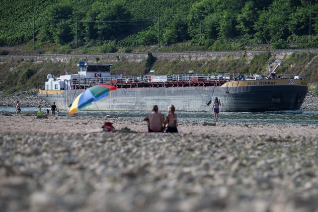 <p>A ship sails through the narrow channel left by the low water in the Rhine while people watch from the sandbanks in Osterpai, Germany, August 16, 2022</p>