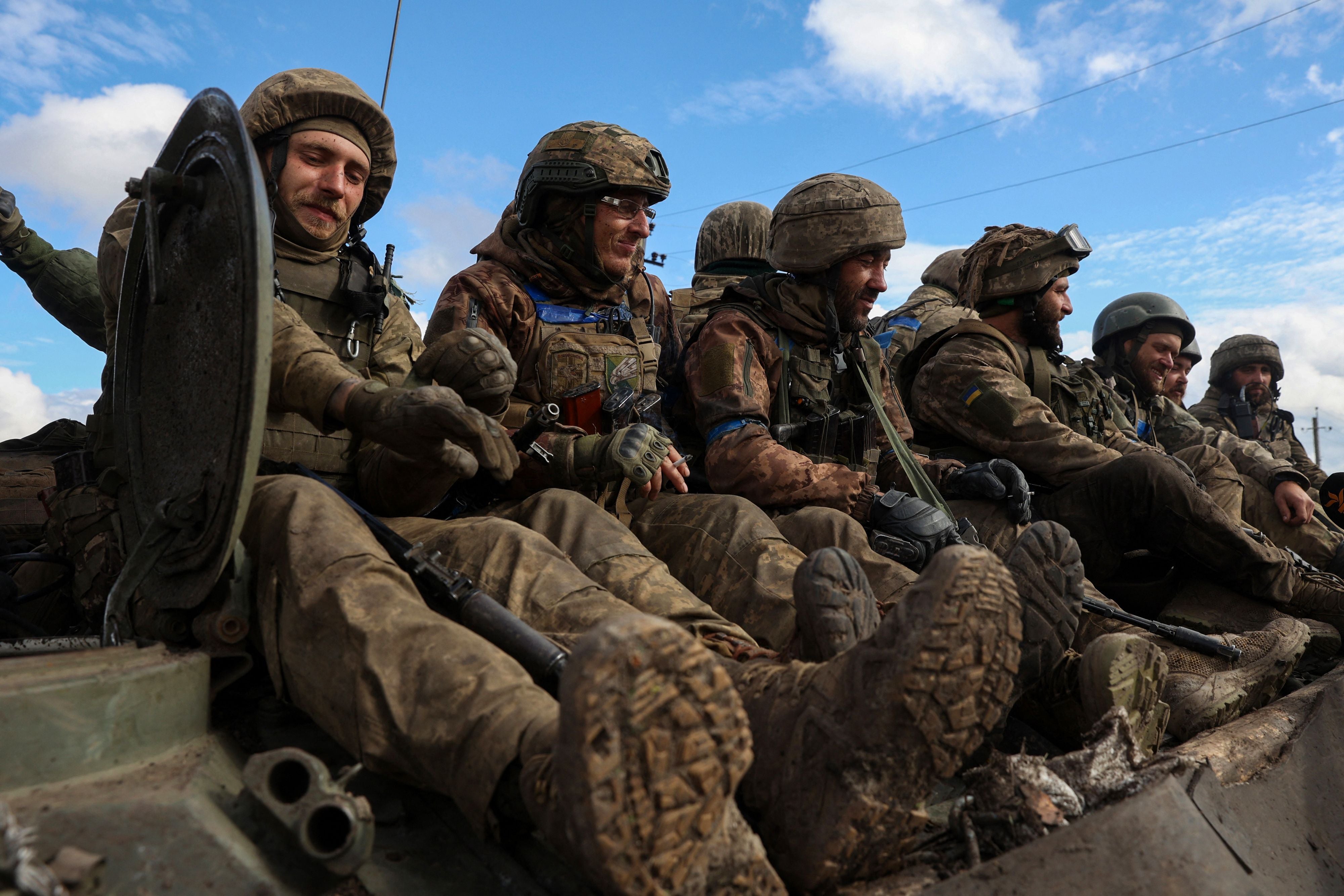 Ukrainian soldiers sit atop a personnel armoured carrier on a road near Lyman, Donetsk