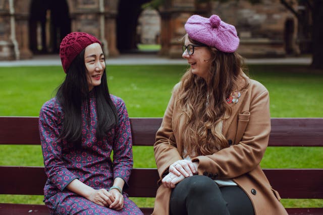 Two women model beanies inspired by the Glasgow University cloisters (University of Glasgow/PA)