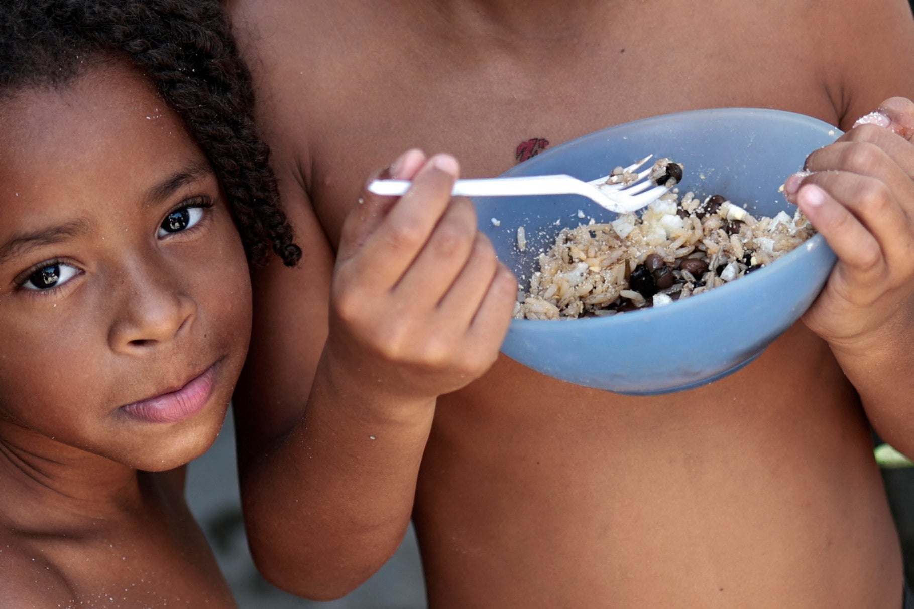 Thawanny Silva de Souza, 6, and Rafael Silva de Souza, 9, eat a lunch of rice, beans and egg in their family’s house, in the Arco Iris favela in Recife, Brazil